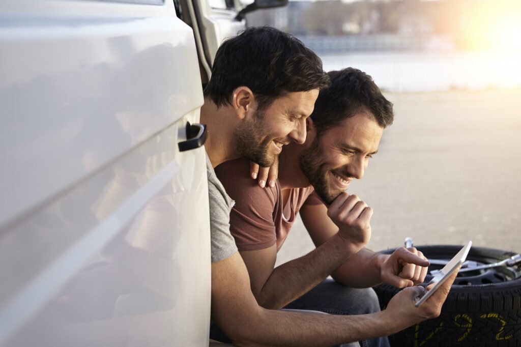 Two men sitting in car looking at digital tablet
